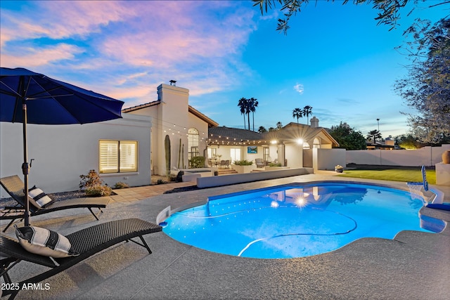 pool at dusk featuring a patio area, fence, and a fenced in pool