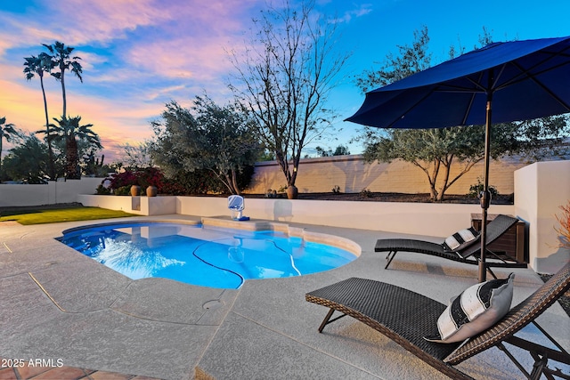 pool at dusk featuring a patio and a fenced backyard
