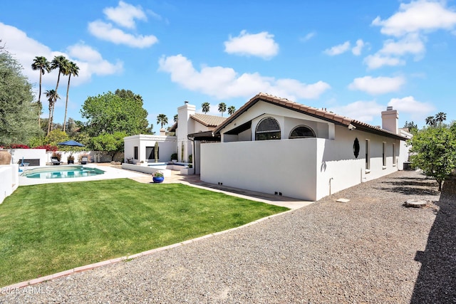 rear view of property featuring a fenced backyard, stucco siding, a lawn, a patio area, and a chimney