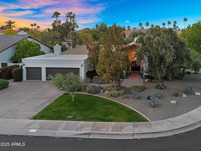 view of front of house featuring stucco siding, a front yard, a chimney, a garage, and concrete driveway