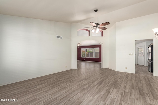 7839 E Milagro Ave, Mesa, AZ 85209 - empty room with ceiling fan, light wood-style flooring, arched walkways, and high vaulted ceiling