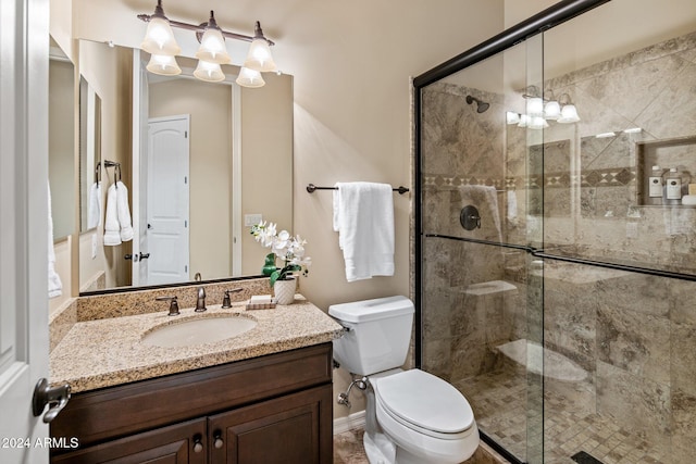 bathroom featuring a shower with door, vanity, and toilet