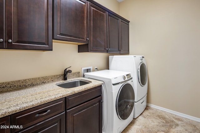 clothes washing area with cabinets, sink, and separate washer and dryer