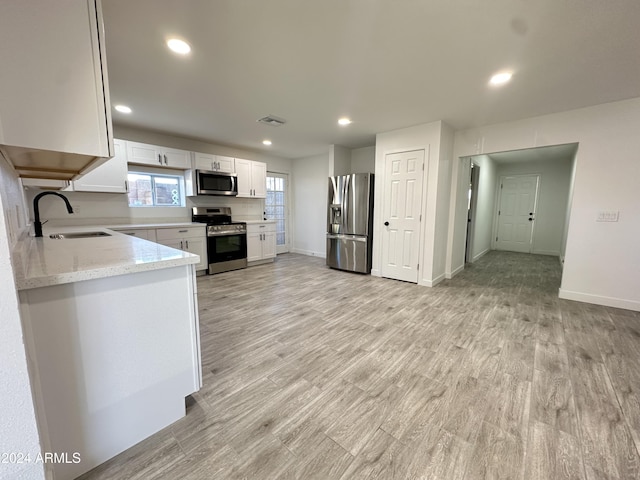 kitchen featuring stainless steel appliances, light hardwood / wood-style floors, white cabinets, and sink