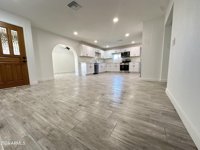 unfurnished living room with ceiling fan and sink