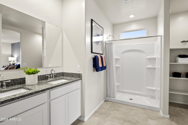 full bathroom featuring a stall shower, baseboards, and double vanity