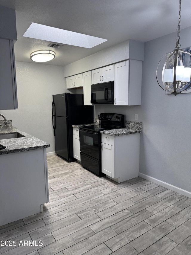 8101 N 107th Ave Unit 26, Peoria, AZ 85345 - kitchen featuring black appliances, a sink, a skylight, light wood finished floors, and stone counters