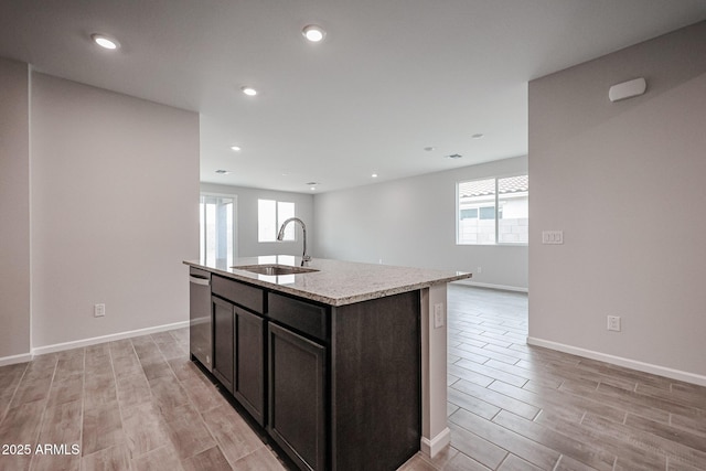 1917 S 246th Ln, Buckeye, AZ 85326 - kitchen featuring a sink, an island with sink, dishwasher, light wood finished floors, and light stone countertops