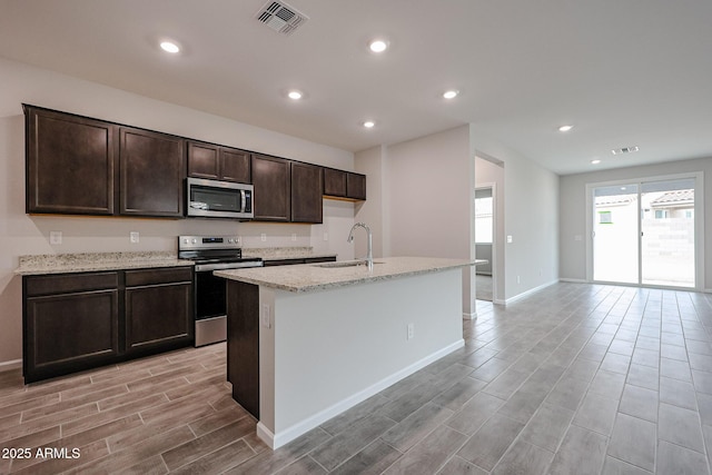 1917 S 246th Ln, Buckeye, AZ 85326 - kitchen featuring a sink, a kitchen island with sink, baseboards, wood finish floors, and appliances with stainless steel finishes