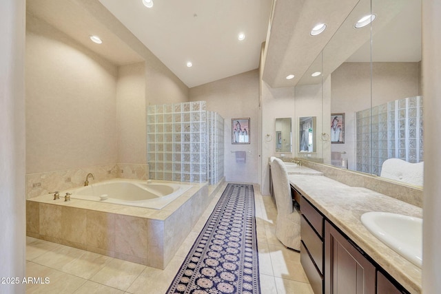 bathroom with tile patterned flooring, vanity, and a relaxing tiled tub