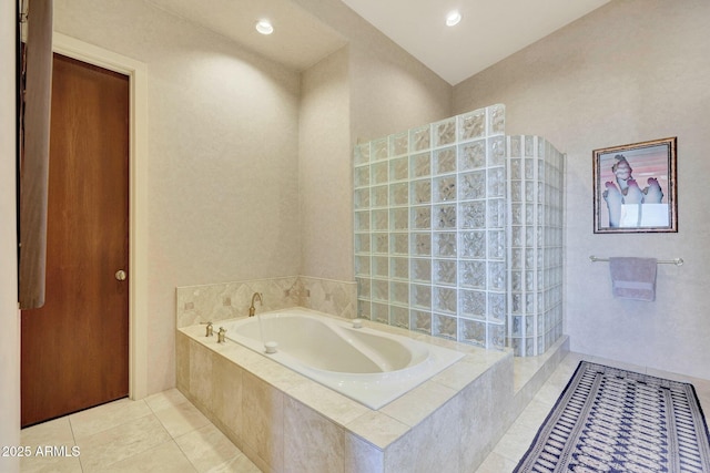 bathroom featuring tile patterned floors and a relaxing tiled tub