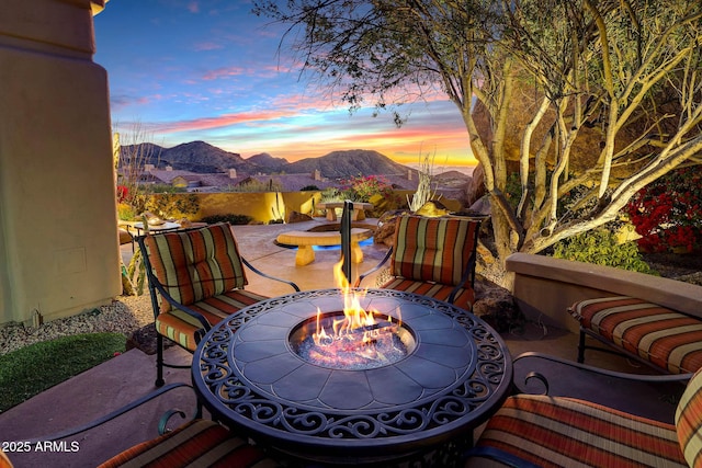 patio terrace at dusk with a fire pit and a mountain view