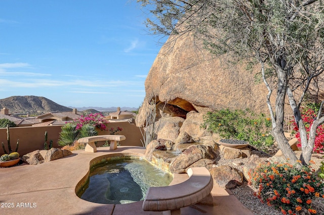 view of pool with a mountain view and a hot tub