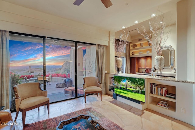 living area with built in shelves and ceiling fan