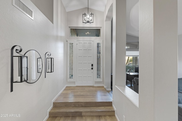 entryway featuring lofted ceiling, a notable chandelier, and wood-type flooring