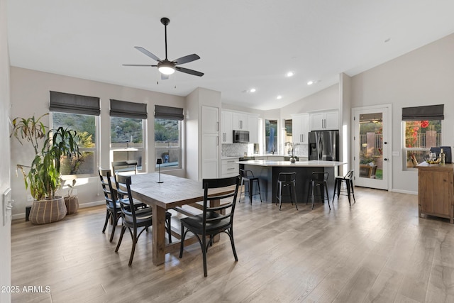 dining room with ceiling fan, lofted ceiling, and light hardwood / wood-style floors