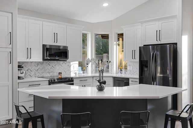 kitchen with white cabinets, a breakfast bar, dishwasher, and electric range