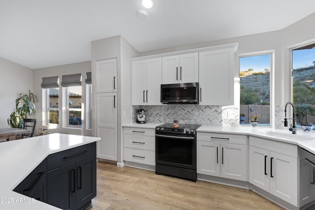 kitchen featuring sink, light hardwood / wood-style flooring, white cabinets, electric stove, and backsplash