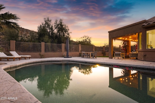 pool at dusk with a patio area