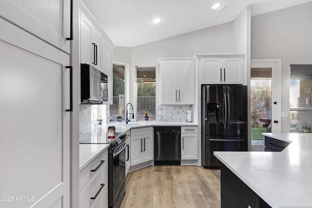 kitchen featuring vaulted ceiling, a healthy amount of sunlight, white cabinets, and black appliances