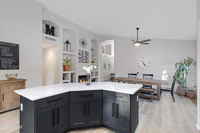 kitchen featuring ceiling fan, a kitchen island, light hardwood / wood-style floors, and built in shelves