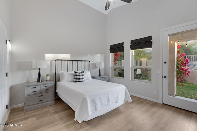 bedroom with ceiling fan, light hardwood / wood-style flooring, and a high ceiling