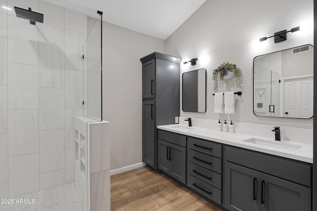 bathroom featuring tiled shower, wood-type flooring, and vanity