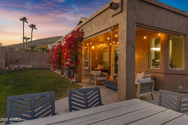 patio terrace at dusk with a yard, an outdoor hangout area, and a mountain view