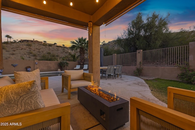 patio terrace at dusk with a pool and an outdoor living space with a fire pit