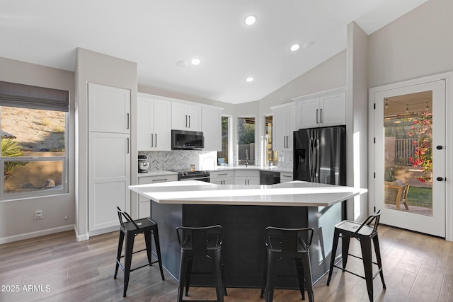 kitchen featuring a kitchen island, white cabinetry, appliances with stainless steel finishes, and a breakfast bar