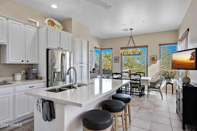 kitchen with sink, white cabinets, tasteful backsplash, an island with sink, and stainless steel fridge with ice dispenser