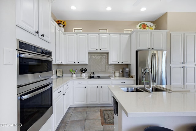 kitchen featuring sink, stainless steel appliances, decorative backsplash, and white cabinetry