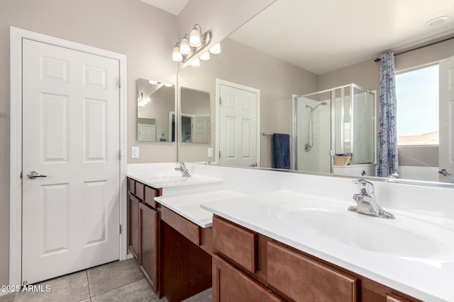 full bathroom featuring tile patterned floors, a sink, a shower stall, and double vanity