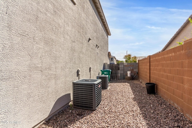 view of property exterior featuring cooling unit, a gate, a fenced backyard, and stucco siding