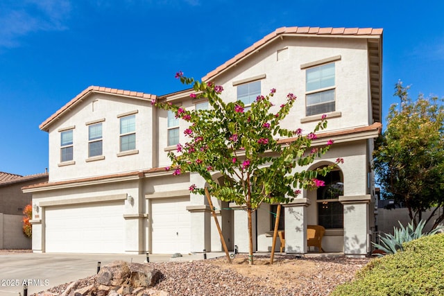 view of front of house with driveway, a tile roof, a garage, and stucco siding