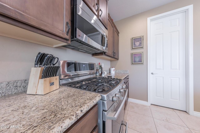 kitchen with light stone counters, appliances with stainless steel finishes, and light tile patterned floors