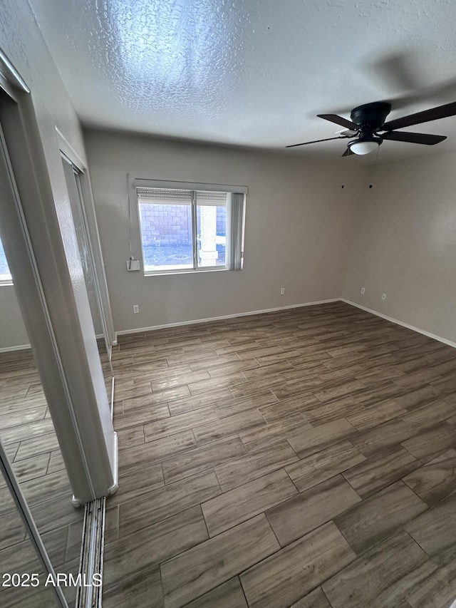 unfurnished room featuring wood finished floors, a ceiling fan, and baseboards