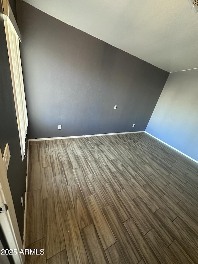 empty room featuring dark wood-type flooring and baseboards
