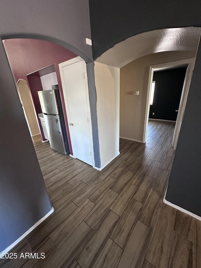 interior space with arched walkways, dark wood-style floors, and baseboards