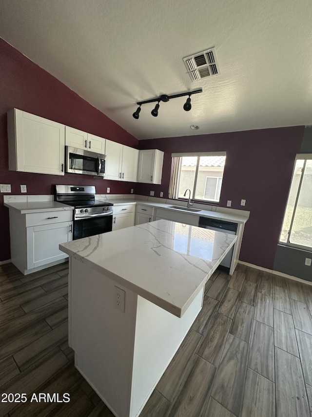 kitchen with rail lighting, a sink, stainless steel appliances, dark wood finished floors, and visible vents