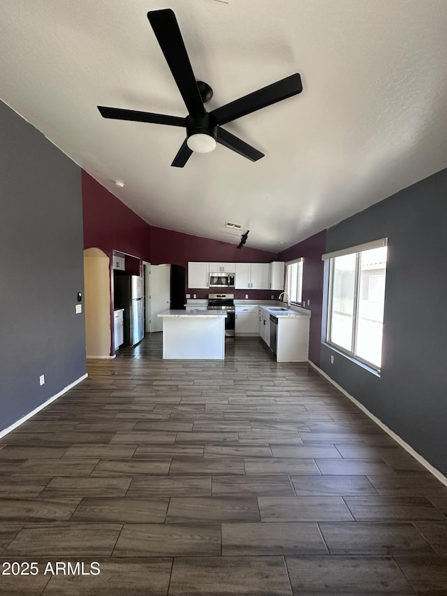 kitchen featuring lofted ceiling, ceiling fan, stainless steel appliances, a kitchen island, and white cabinetry