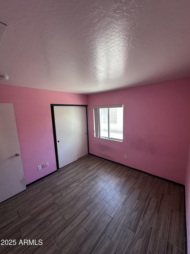 unfurnished bedroom featuring wood finished floors, a textured ceiling, and a closet