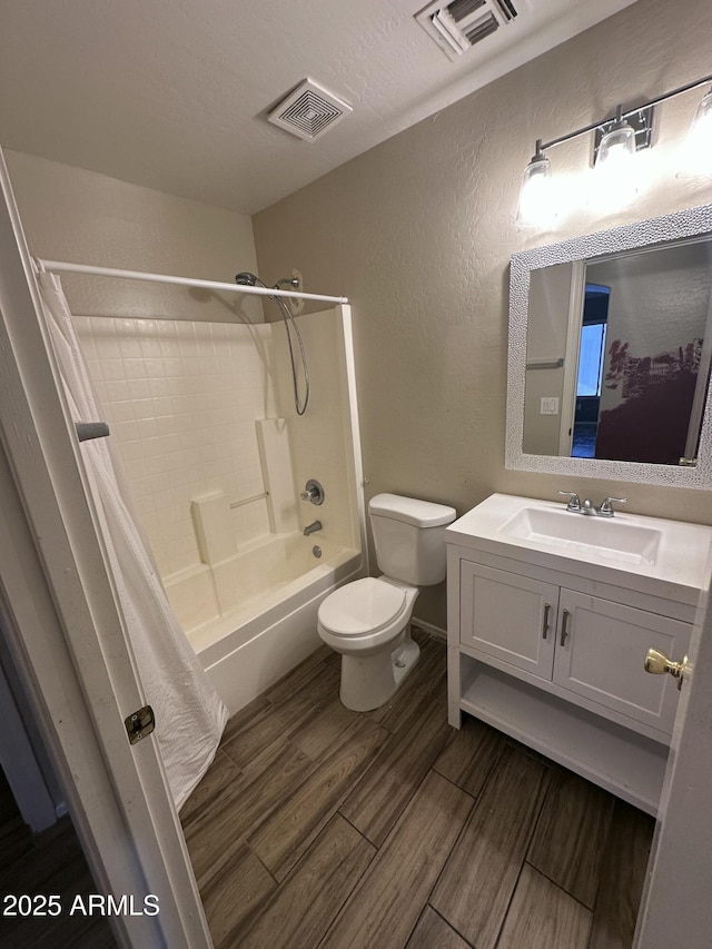 full bath featuring toilet, a textured wall, wood finished floors, and visible vents