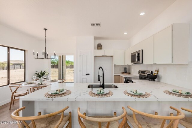 4561 E Red Bird Ln, San Tan Valley, AZ 85140 - kitchen with appliances with stainless steel finishes, a peninsula, light stone countertops, plenty of natural light, and recessed lighting