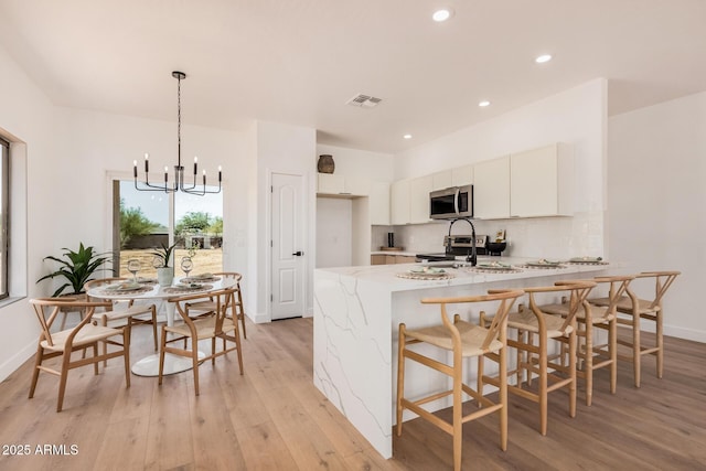 4561 E Red Bird Ln, San Tan Valley, AZ 85140 - kitchen featuring stainless steel microwave, light wood-style floors, a peninsula, light stone counters, and a chandelier