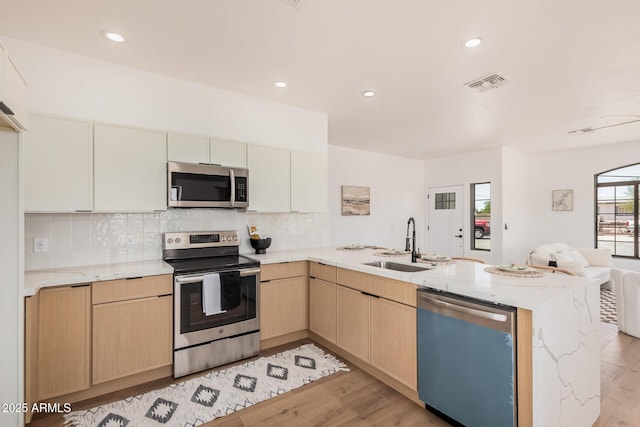 4561 E Red Bird Ln, San Tan Valley, AZ 85140 - kitchen with stainless steel appliances, a peninsula, open floor plan, light brown cabinetry, and light wood finished floors