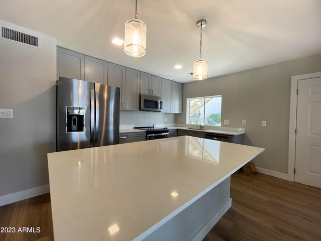 kitchen with gray cabinetry, sink, appliances with stainless steel finishes, decorative light fixtures, and a kitchen island