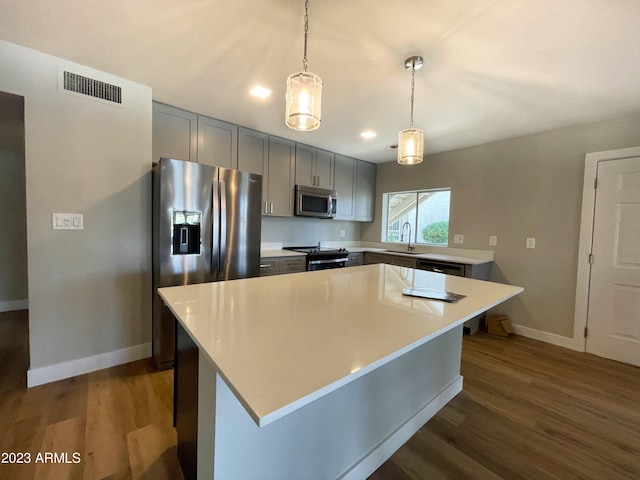 kitchen featuring dark hardwood / wood-style flooring, a kitchen island, hanging light fixtures, and appliances with stainless steel finishes