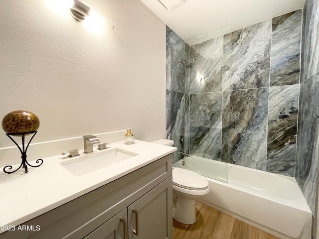 full bathroom featuring vanity, hardwood / wood-style floors, tiled shower / bath combo, and toilet