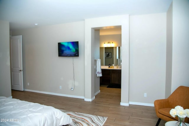 bedroom with connected bathroom and light hardwood / wood-style floors